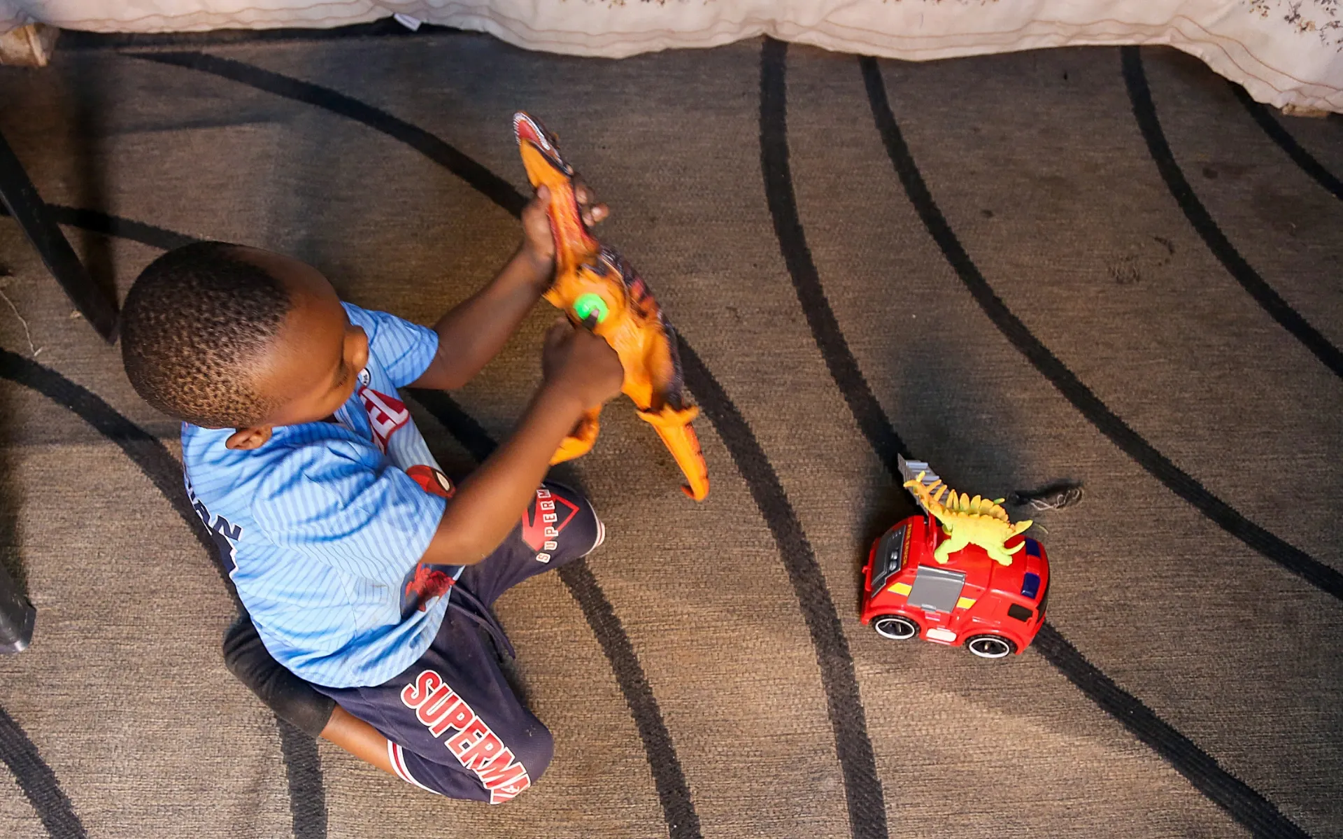 A young boy plays with his toys on the ground at his home in KuGompo City, East London, Eastern Cape, South Africa, on 27 August 2026. The boy is unable to walk and spends much of his time on the ground. His mother, *Zoe, gave birth to him at Frere Hospital after enduring two weeks of labour before hospital staff admitted her. Photograph: Mark Andrews/SA|AJP